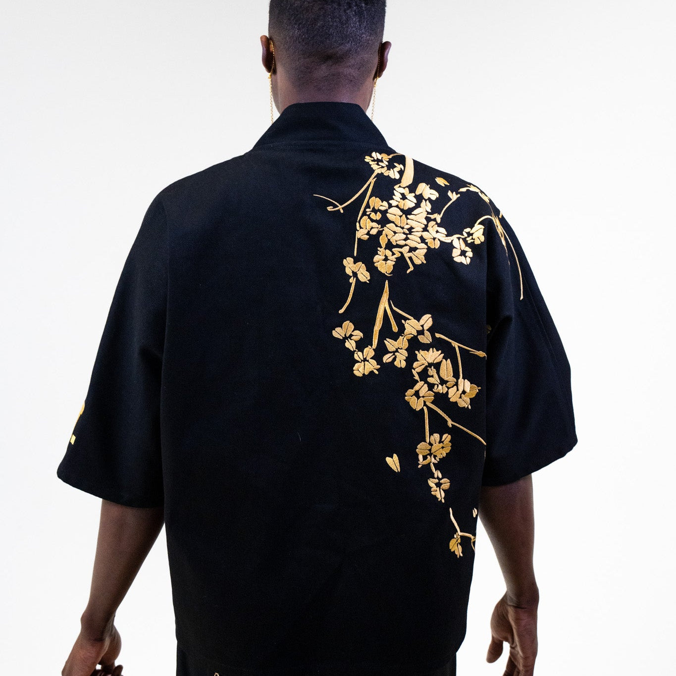 Person wearing the black YST kimono outfit with gold floral embroidery on the back against a white background