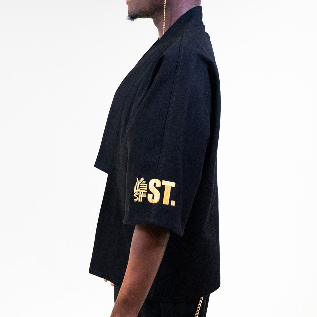 Yelsh model wearing our limited edition gold embroidered kimono outfit with 'YST.' logo, holding a red bag on a white background