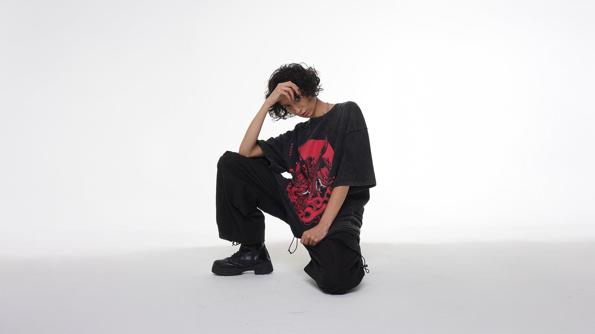 Yelsh Street Model wearing a black t-shirt with a red Oni graphic and black pants on a white background